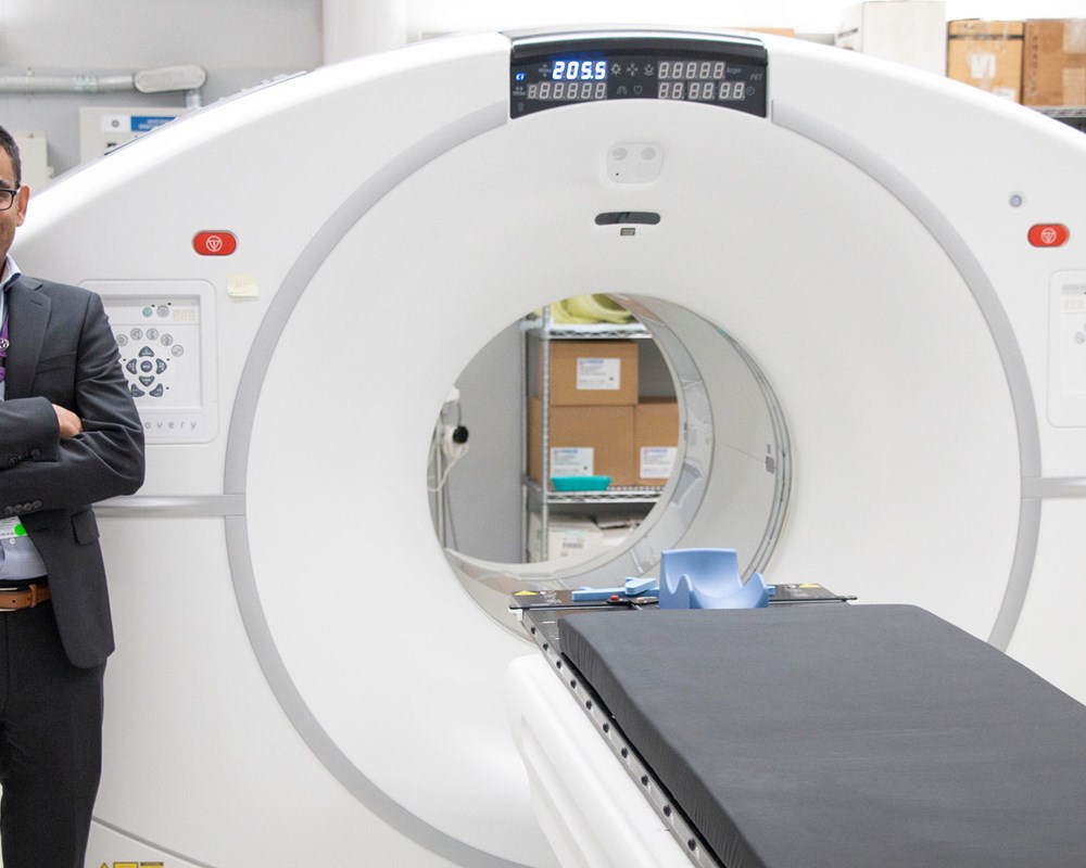 Dr Neil Vasdev standing in front of a PET scanning machine