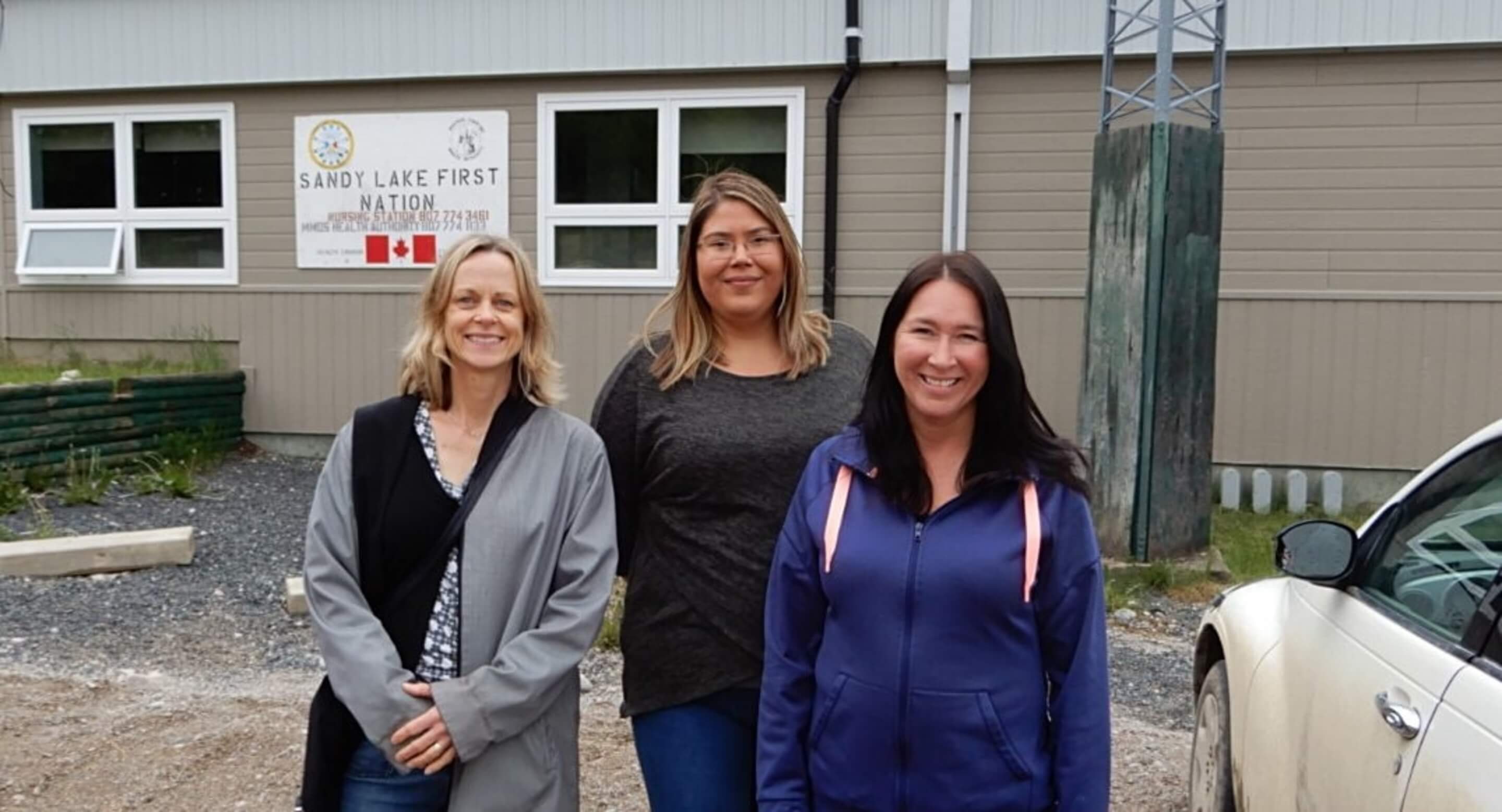 Dr. Samantha Wells, Krystine Abel and Dr. Renee Linklater outside the nursing station in Sandy Lake First Nation