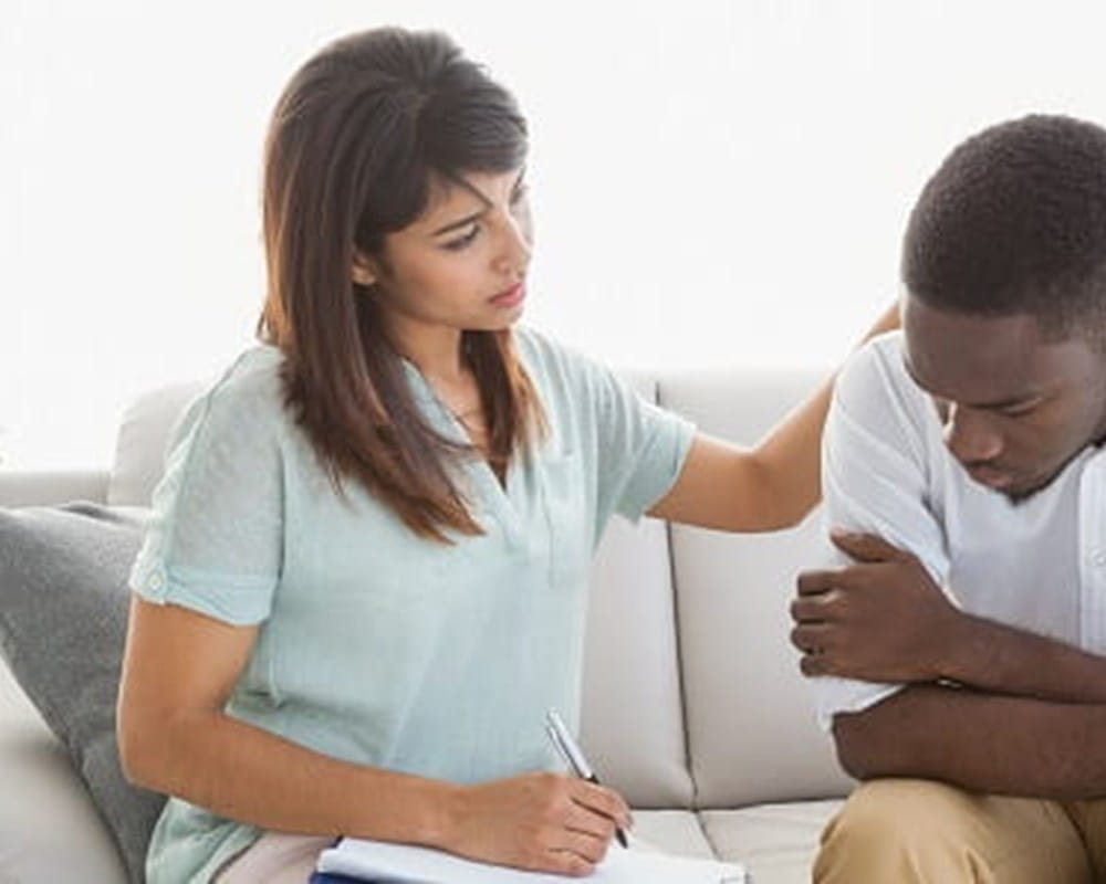 A coloured female physician consoling a coloured patient during a therapy session.