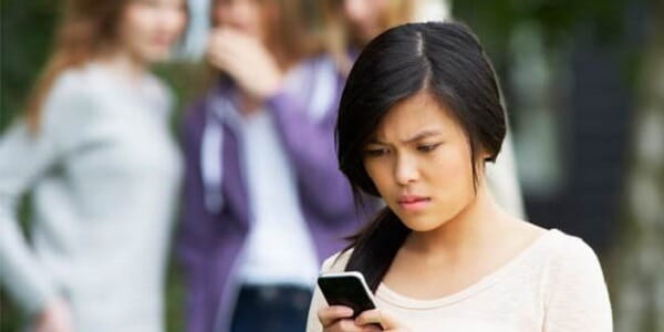 A young girl looking at her phone and is upset about something on the screen. 