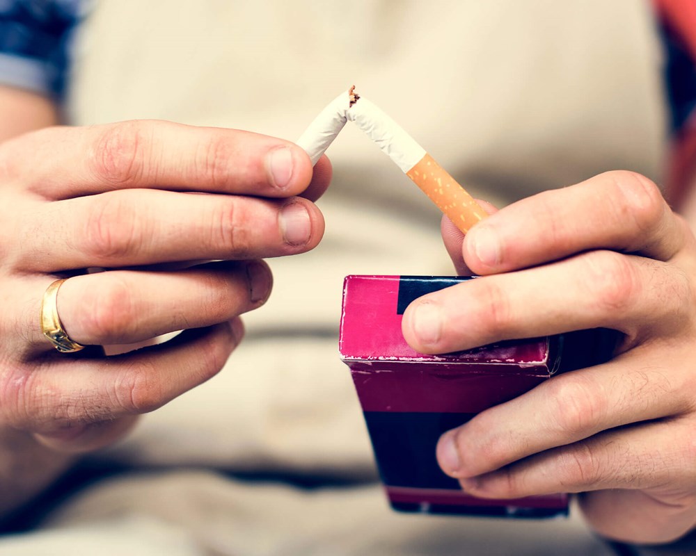 Photo of someone snapping a cigarette in half.