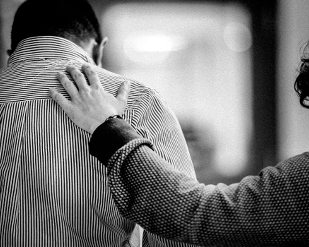 Woman putting her hand on the back of person in distress