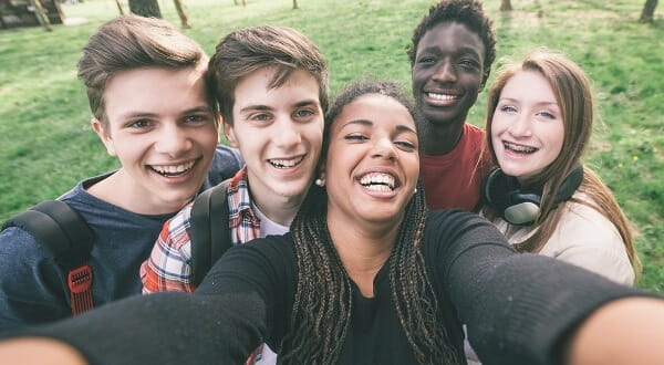 A diverse group of teens taking a smiling selfie. 