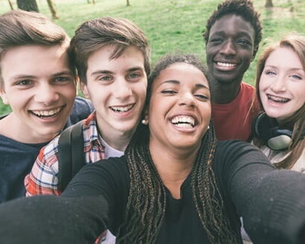 A diverse group of teens taking a smiling selfie.