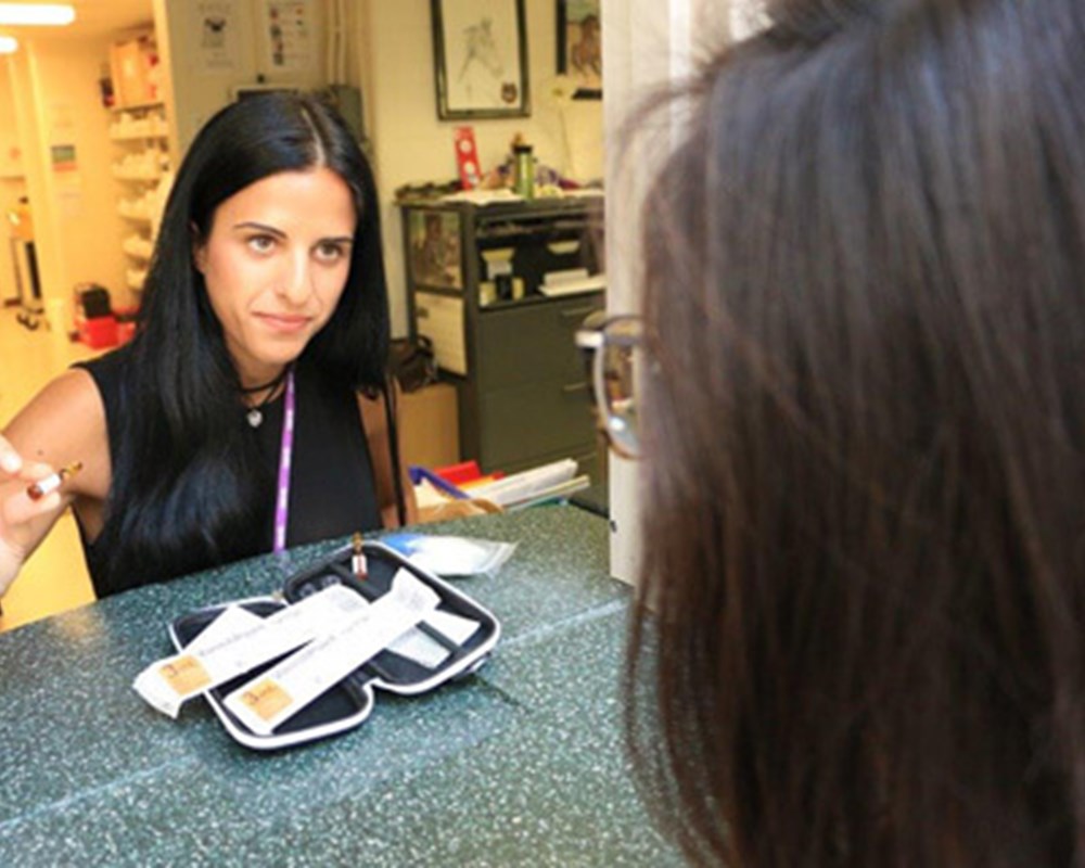 A female pharmacist of CAMH handing over a prescription medication to her client and explaining it to her over the counter.