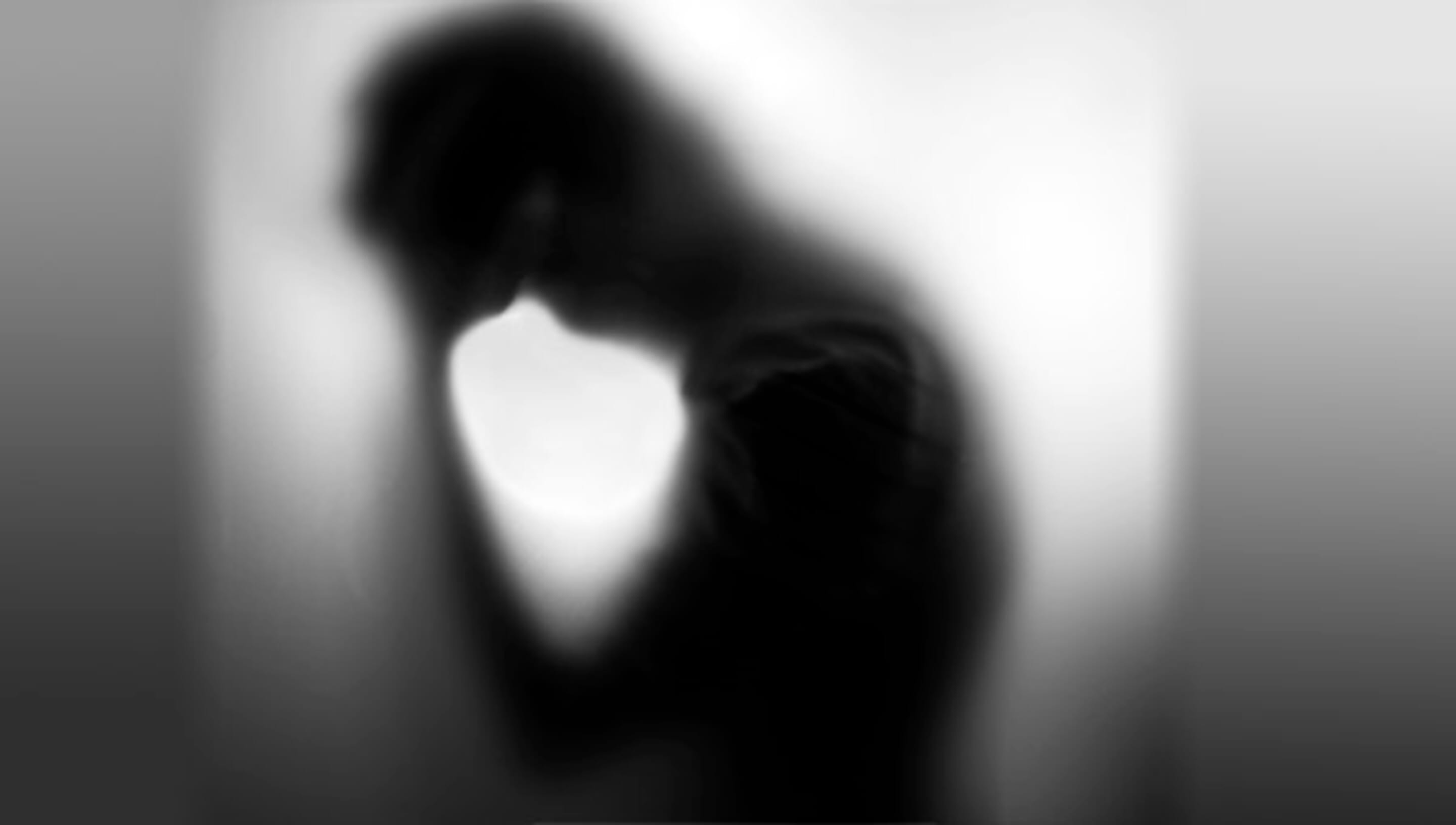 A blurry silouette of a man with his hands on his forehead. 