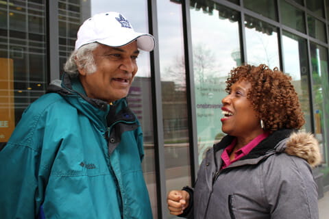 A nurse and her client, Rohan wearing winter coats and laughing outside. 