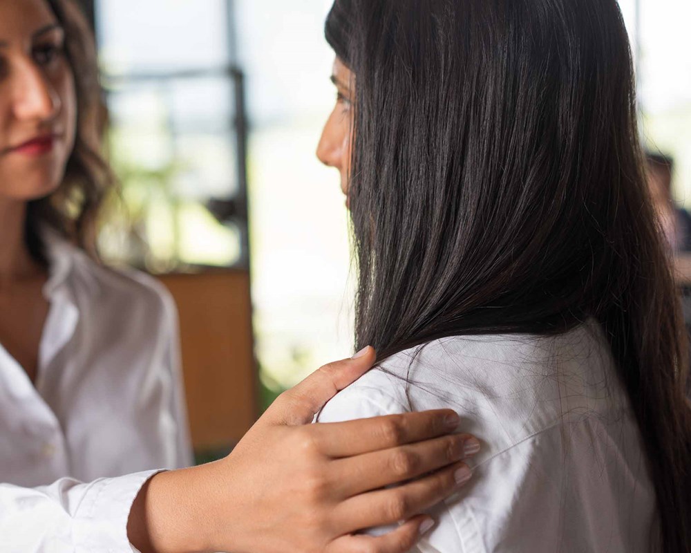 Photo of a woman holding the shoulder of another woman supportively.