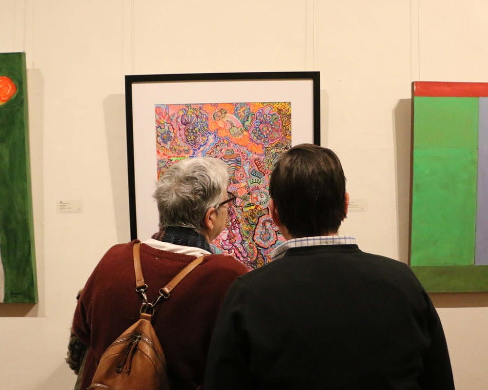 Photo of people looking at art on the wall