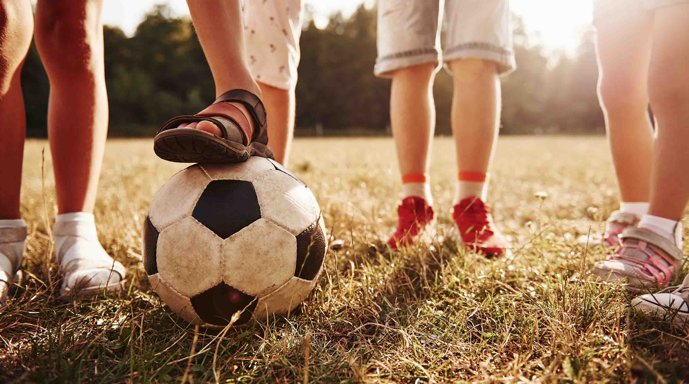 View of kids in a field on a sunny day with soccer ball.