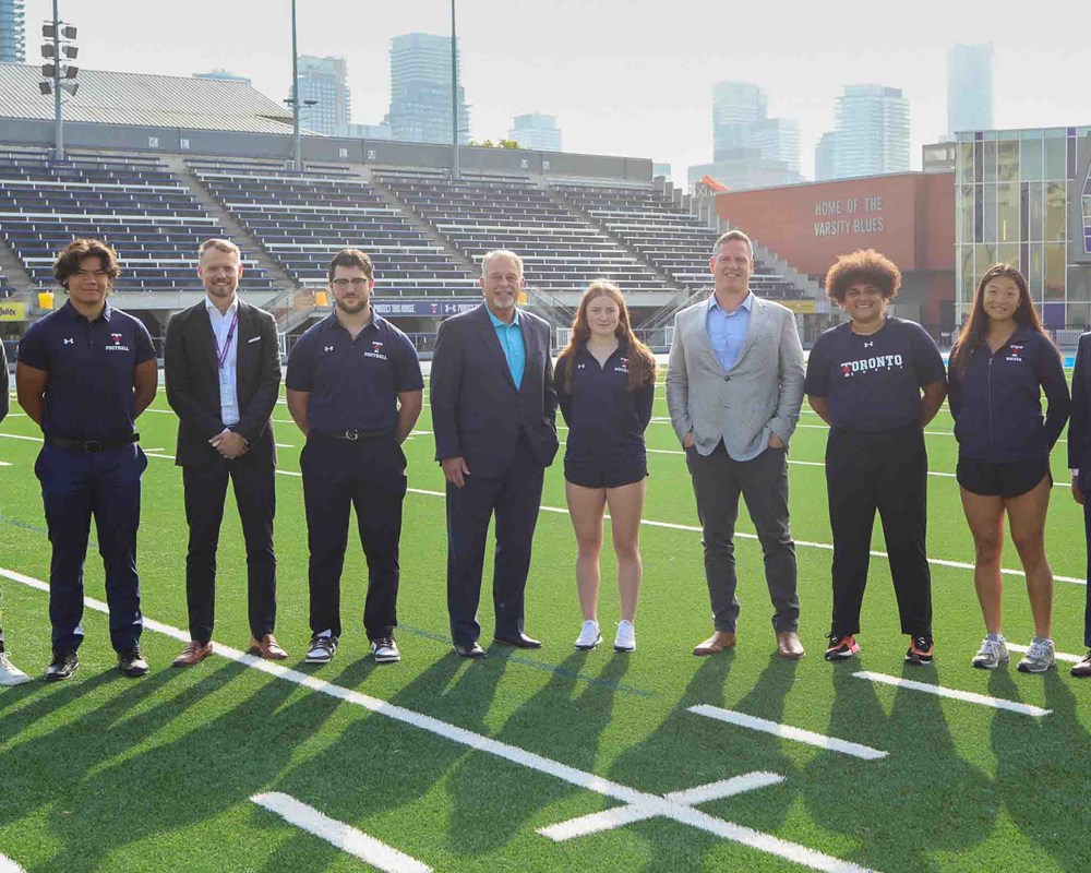 Group photo of Minister Lumsden, Tim Fleiszer, Dr. Neil Vasdev, Dr. Jesse Young, and U of T Student Athletes