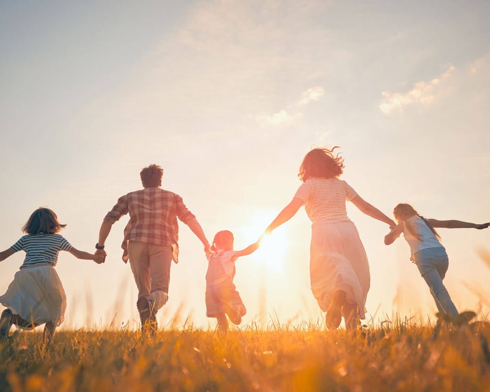 People running in a field at sunrise or sunset.