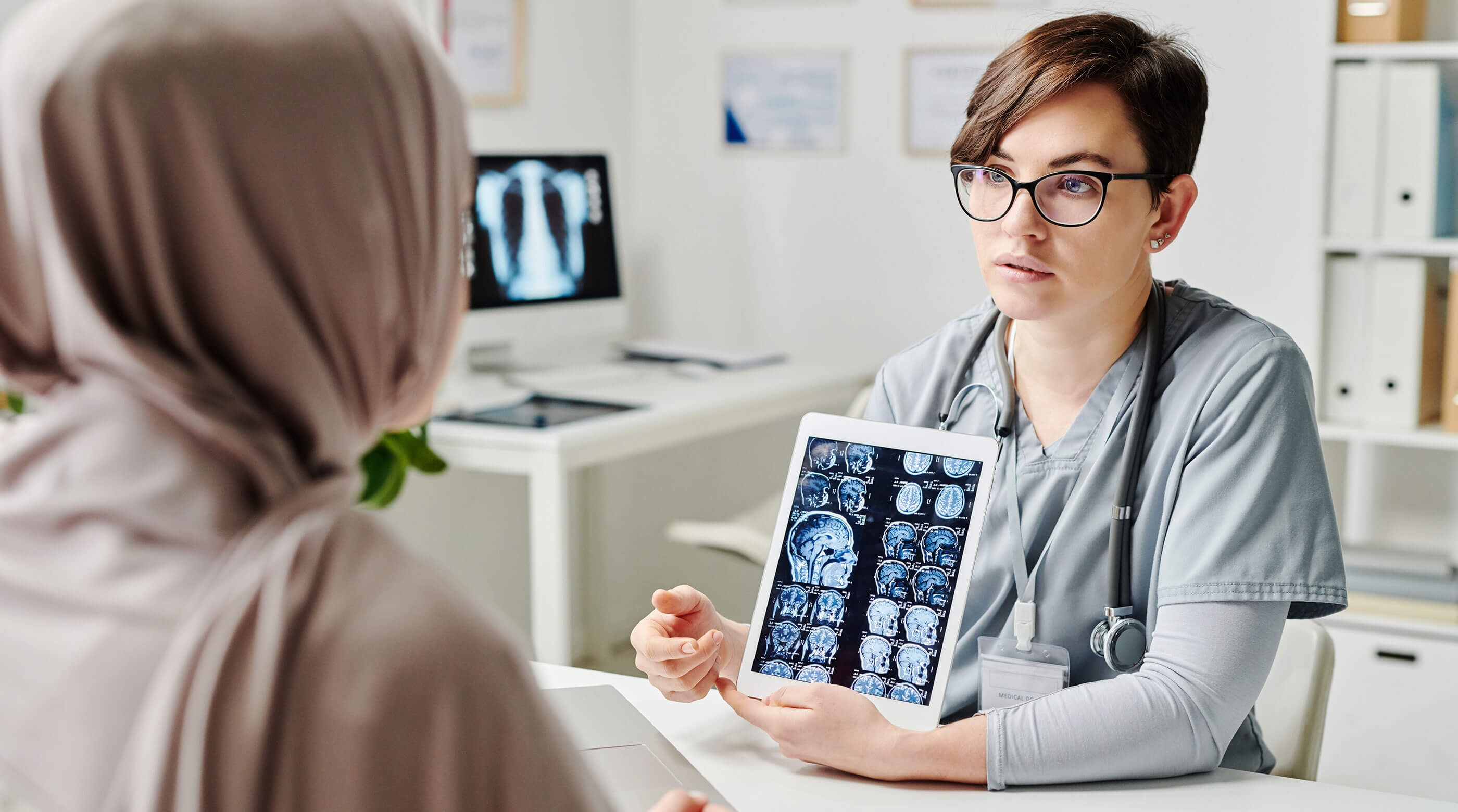 Photo of a radiologist showing brain images to a patient on a tablet