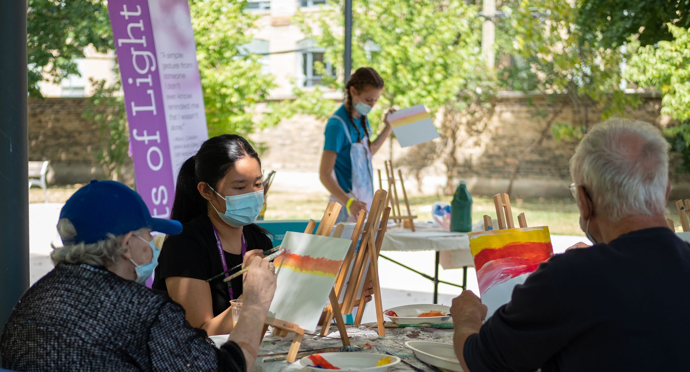 Clinician with patients painting outdoors